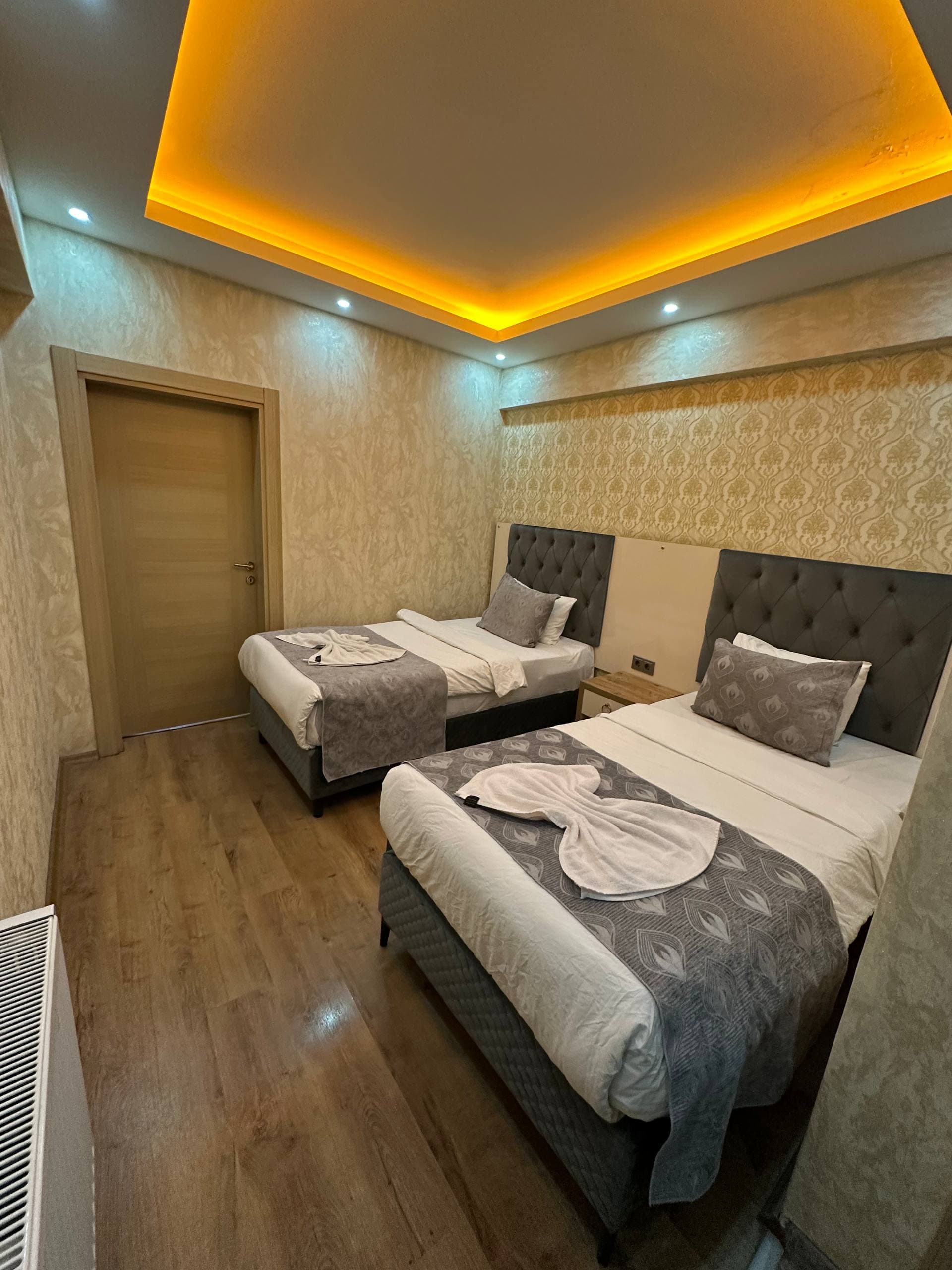 Damask desenli duvar kâğıdı önünde iki tek kişilik yatak