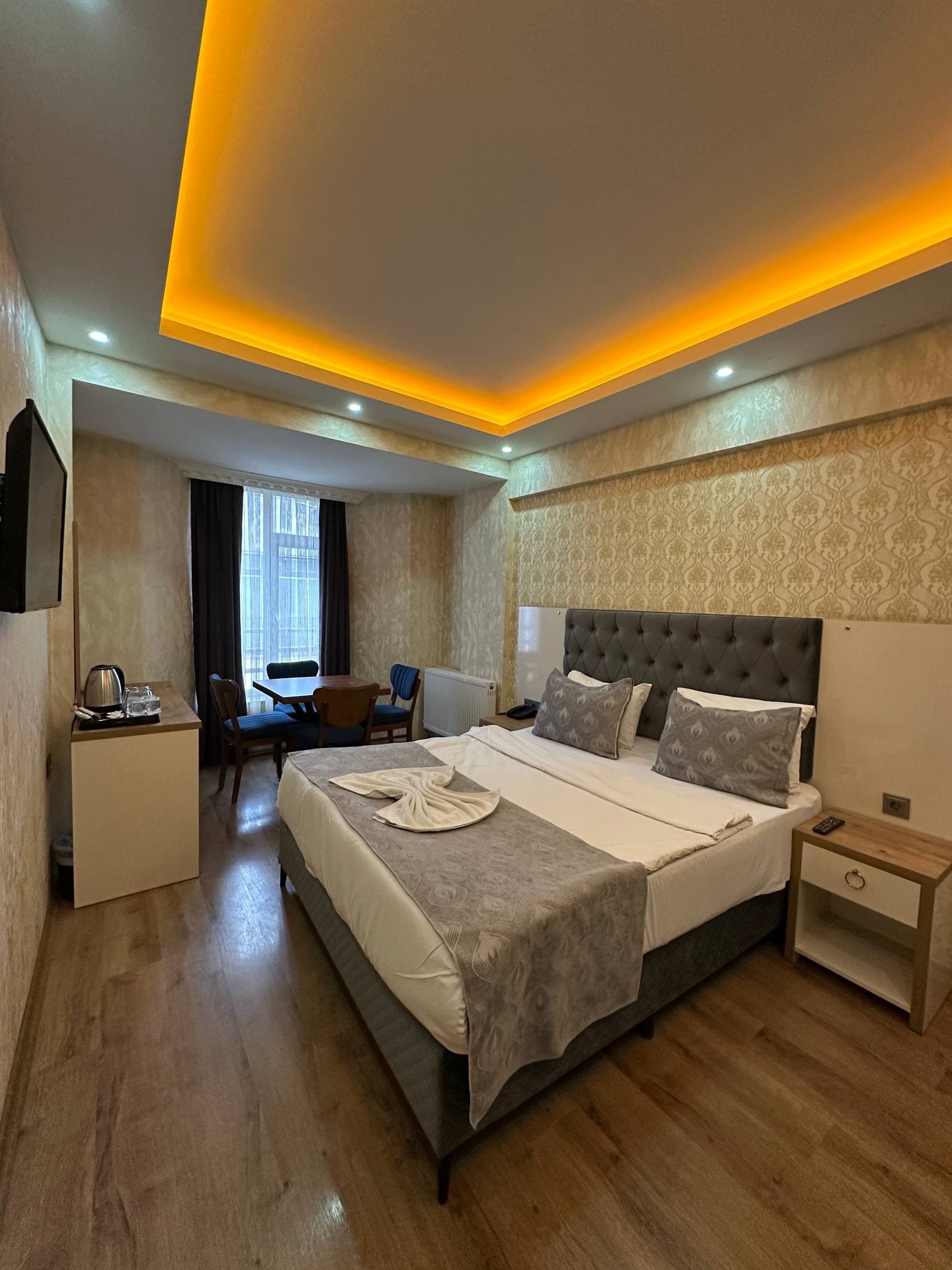 King size yataklı bir oda; süslü duvar kâğıdı ve gizli ışıklandırmalı tavan