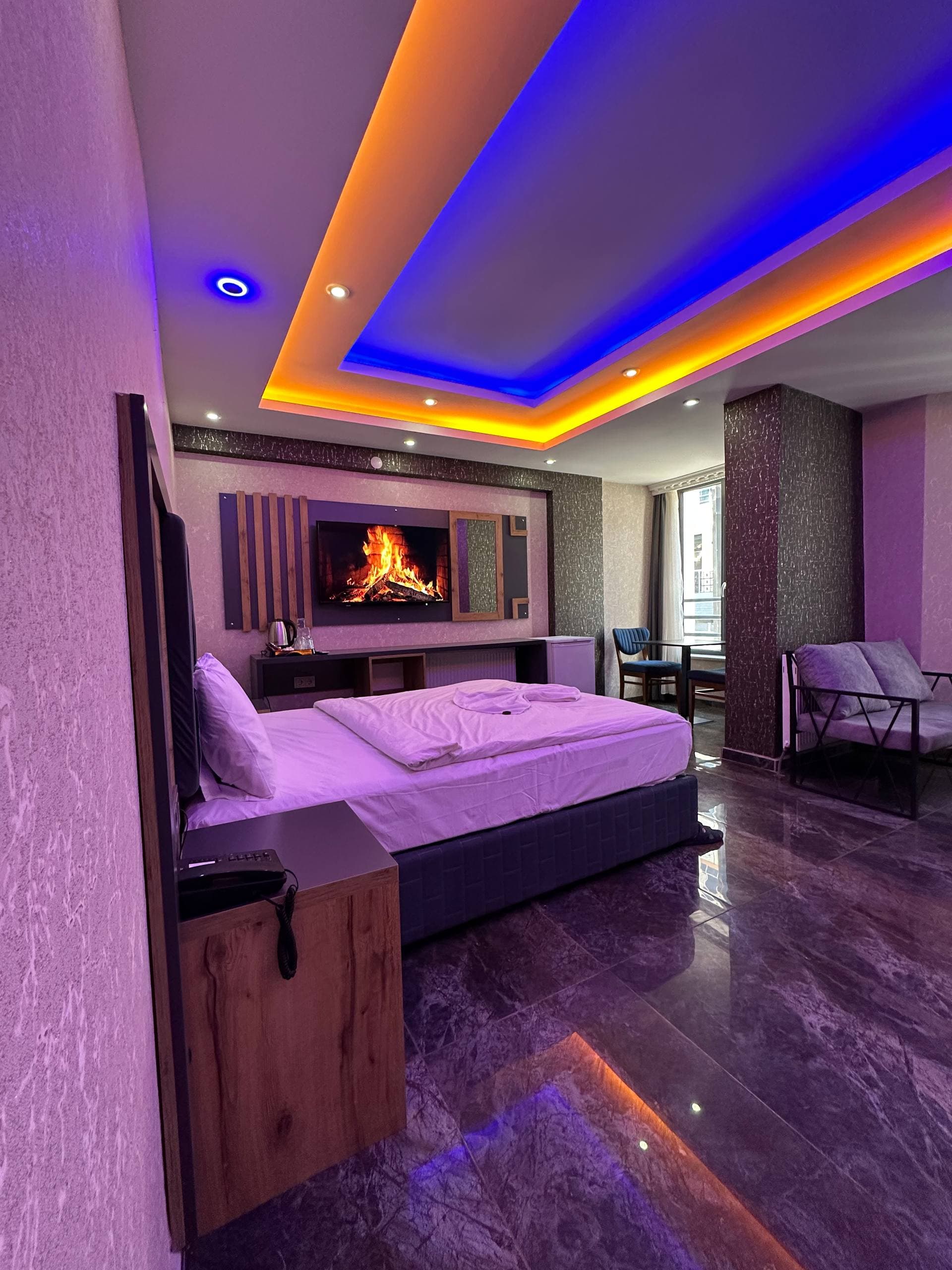 Şömine ekranı ve renkli tavan ışıklandırmasıyla geniş aile odası