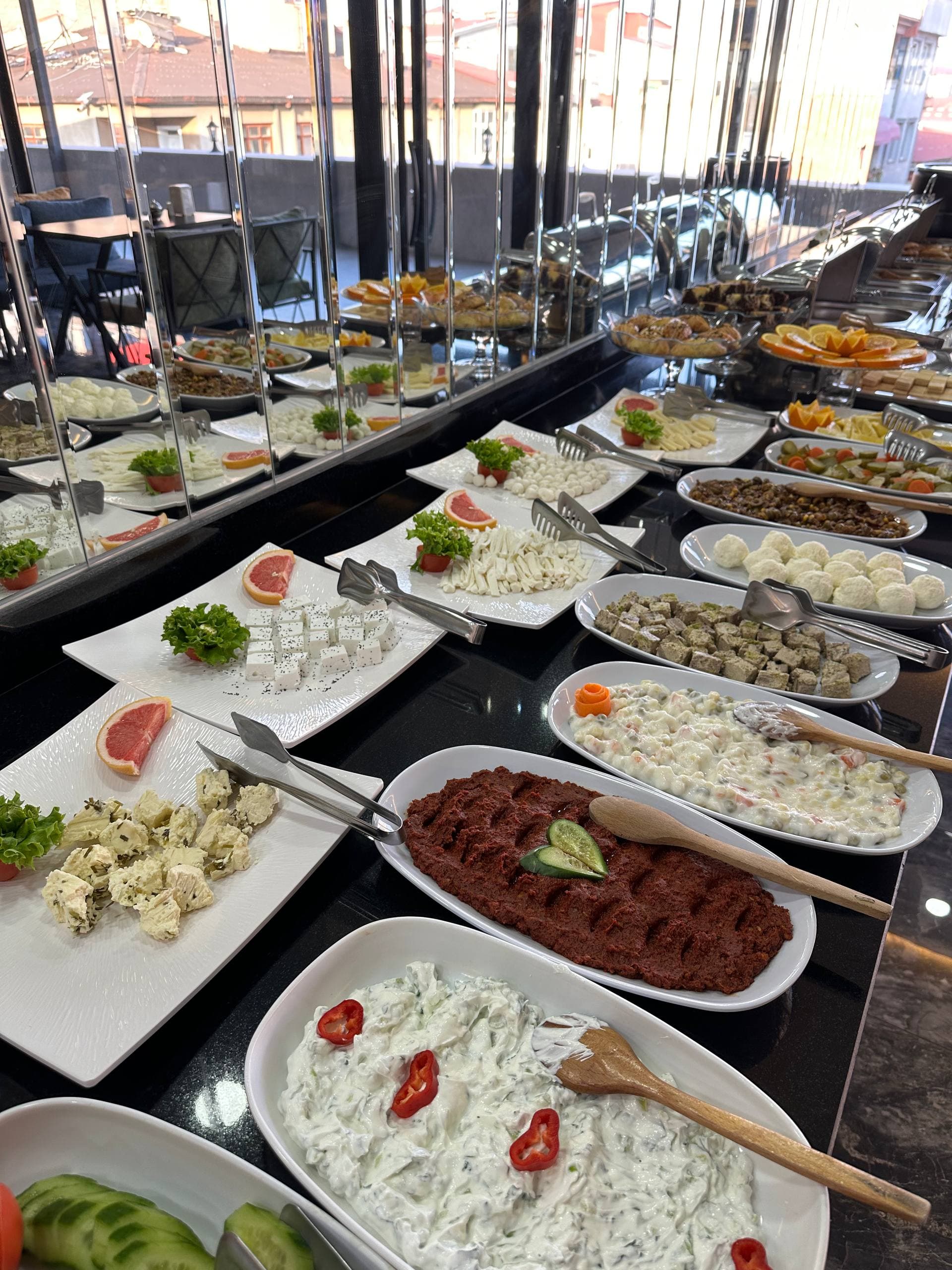 Overhead view of a Van breakfast table with small dishes of cheese, honey, olives, jams, and fresh bread arranged close together.